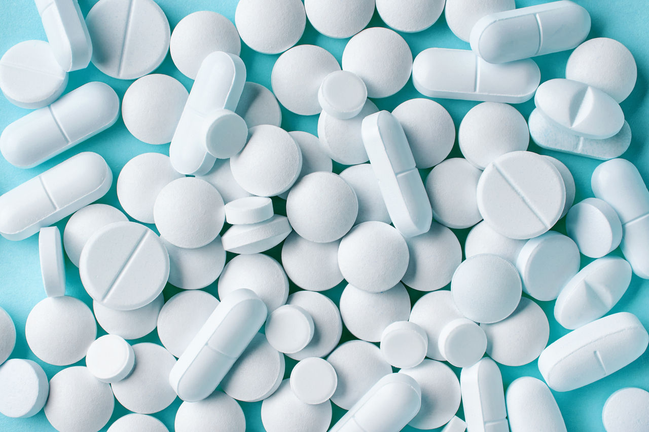 various white pills macro on blue background, top view