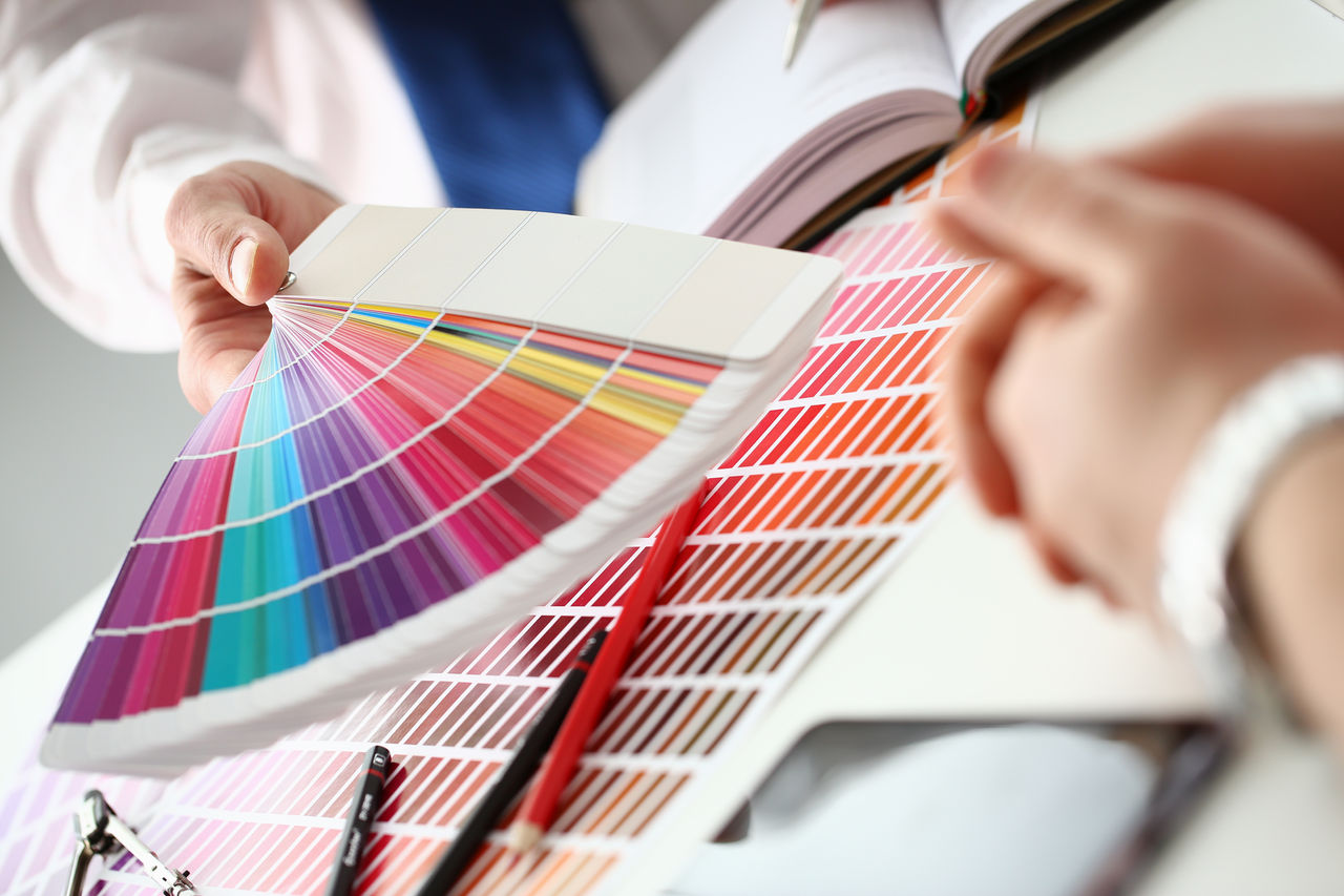 Employee refueling cartridge service holds magnifying glass in hand. Color print of pantone statistics offset organization gives customer an order products for distribution during promotion concept; Shutterstock ID 1232997268; purchase_order: CON; job: New website; client: ; other: 