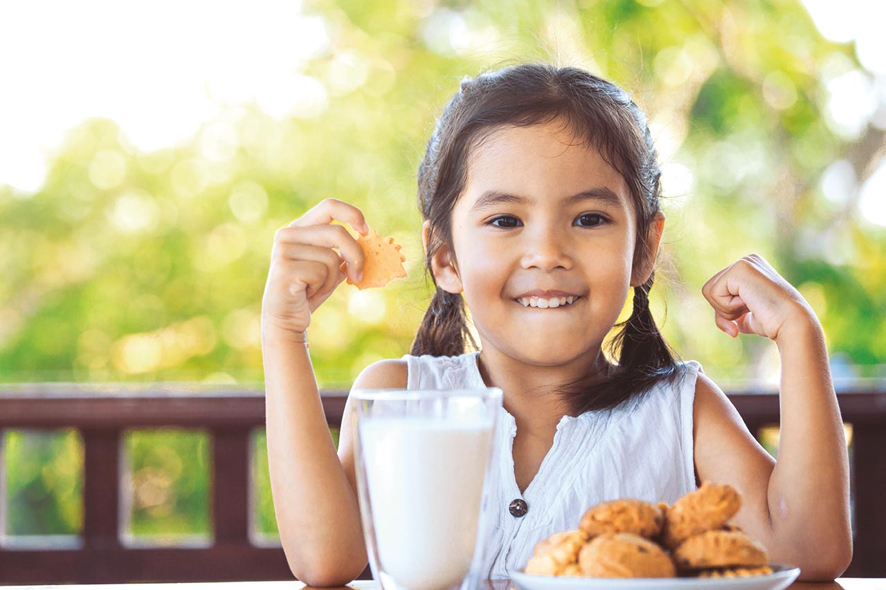 Girl with cookies and a glass of milk looking happy