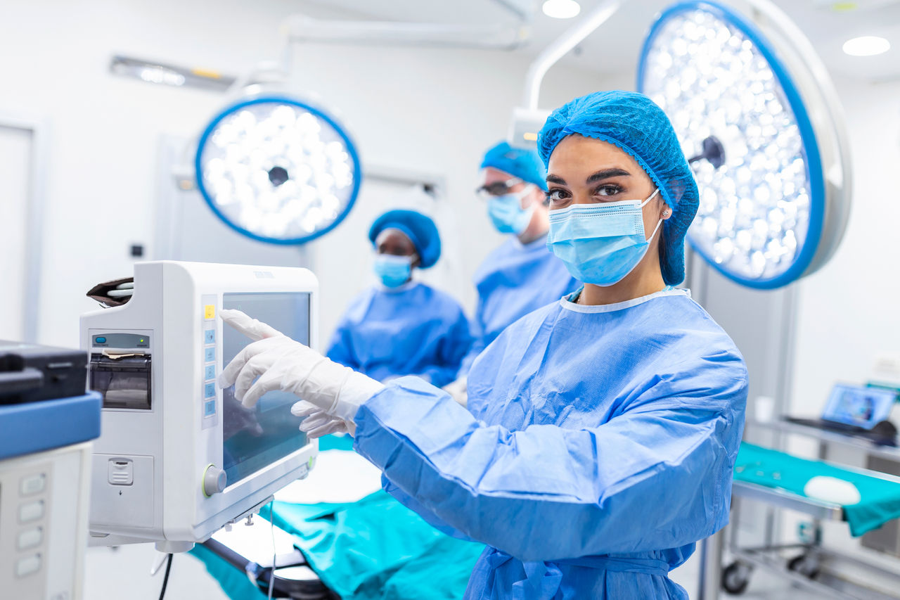 Diverse Team of Professional Surgeons Performing Invasive Surgery on a Patient in the Hospital Operating Room. Nurse Hands Out Instruments to surgeon, Anesthesiologist Monitors Vitals.; Shutterstock ID 1963299028; purchase_order: POL ABR Fibers & Nonwovens; job: ; client: POL ABR Fibers & Nonwovens; other: 