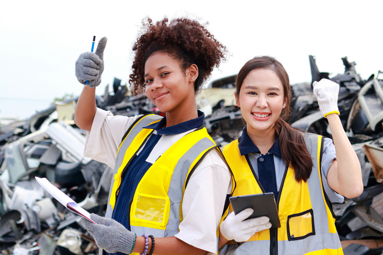 Two engineers standing outdoors behind a pile of plastic waste