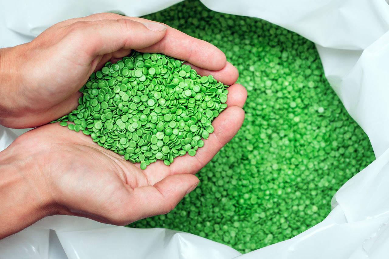 A hands hold or touching biodegradable plastic pellets, plastic polymer dye granules color clear green; Shutterstock ID 1335481439; purchase_order: POL Website_GDS EM page; job: ; client: ; other: 