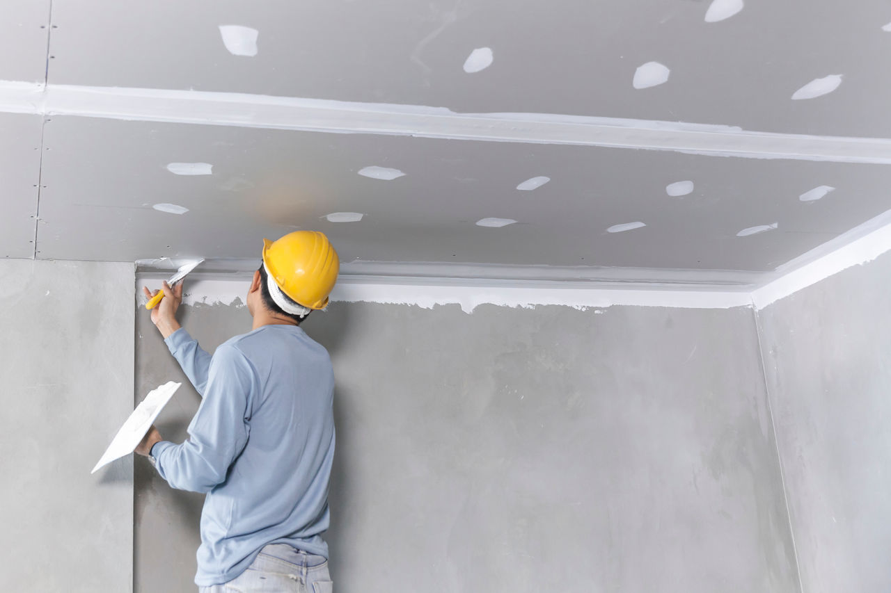 Man with yellow helmet working on a ceiling