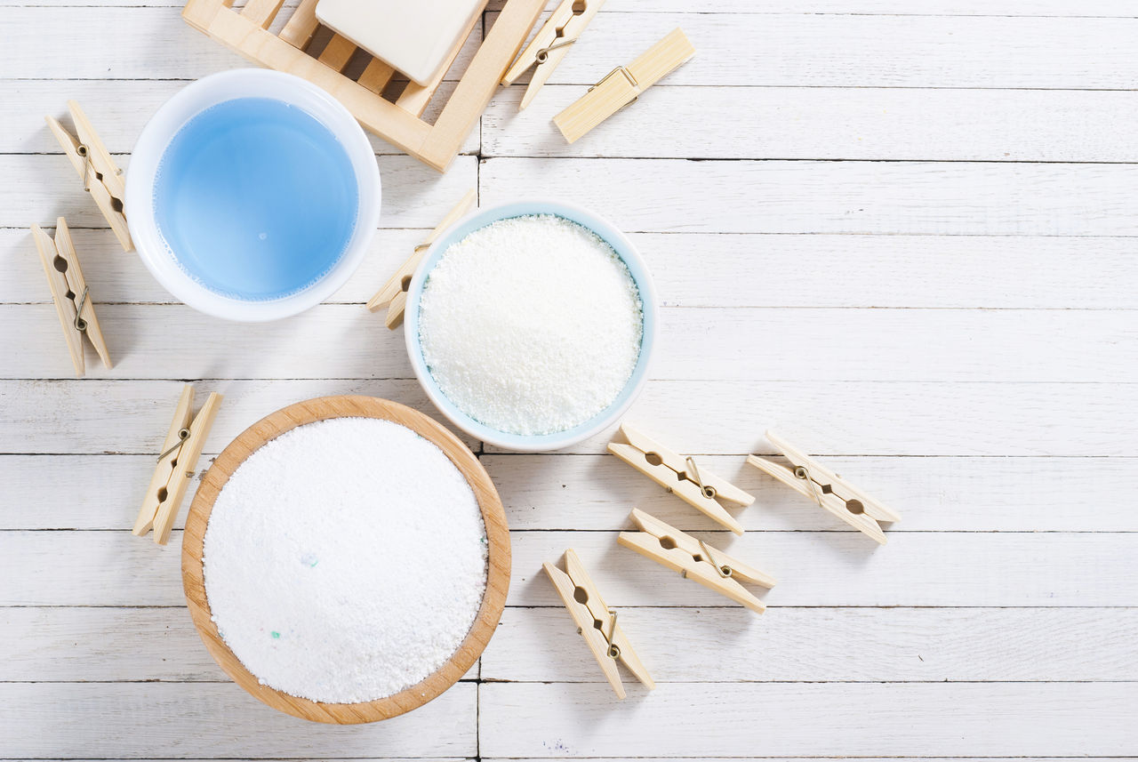 different washing powders, liquid and soap with clothes pins on white wood ; Shutterstock ID 500072440