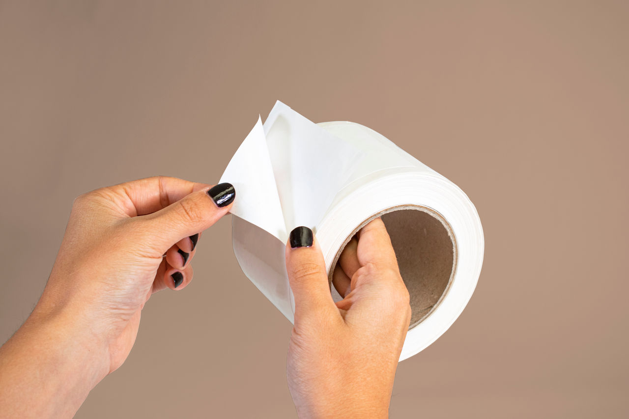 label sticker roll on reel with hand applying; Shutterstock ID 1938067987; purchase_order: POL Website_OmyaPET; job: ; client: ; other: 